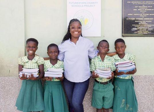 Pupils holding stacks of donated exercise books with a Future Stars staff member