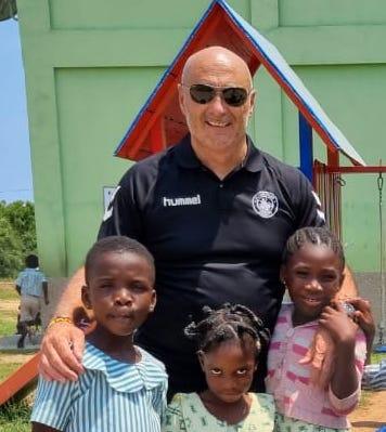 A volunteer with three children outside a school building