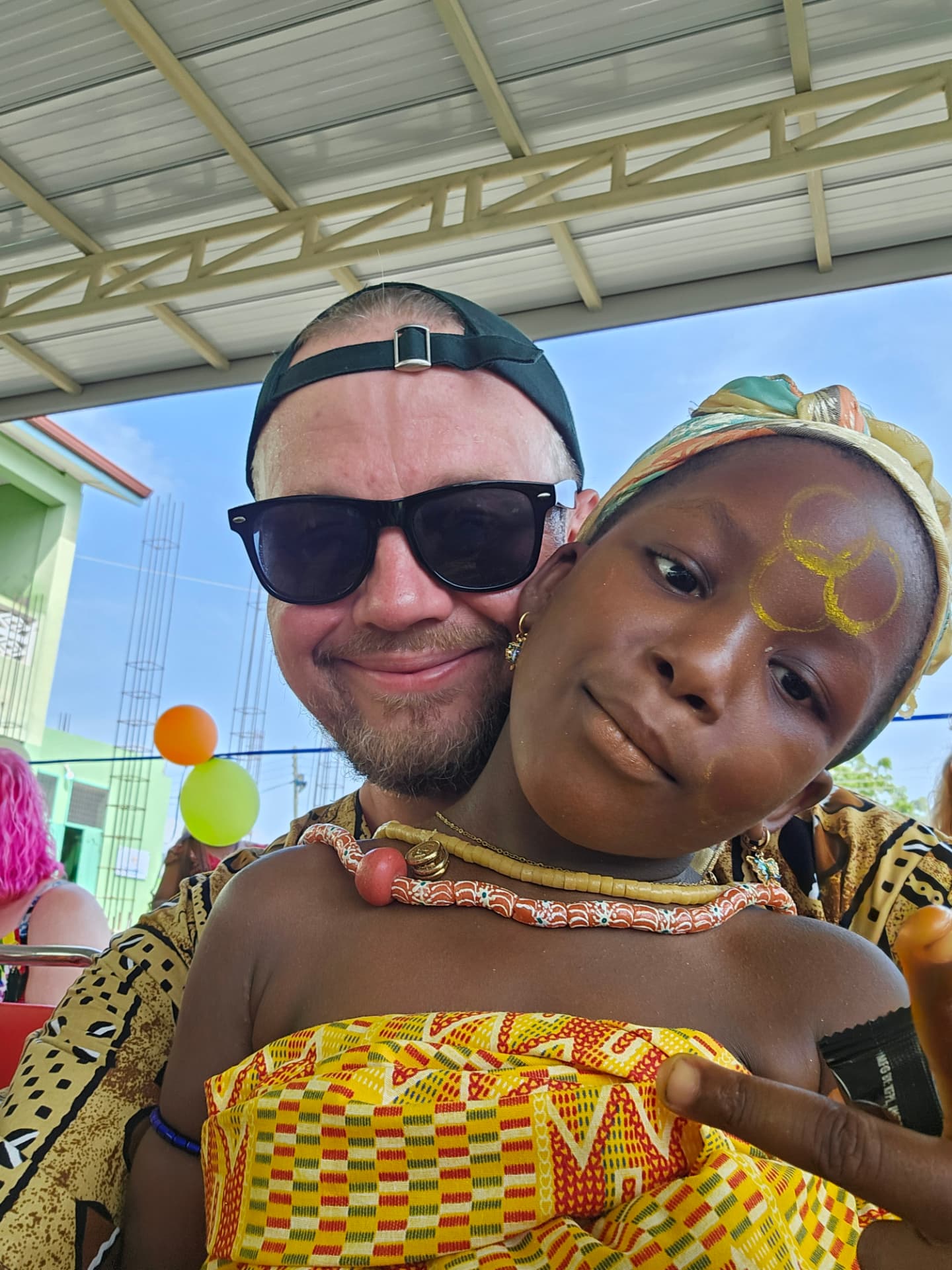 A volunteer and a child in traditional Ghanaian dress at a celebration